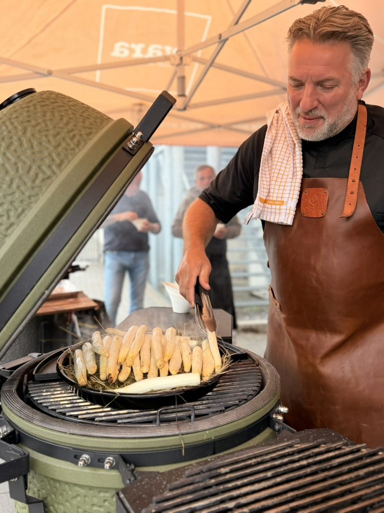 Chef grilt witte asperges op een kamado tijdens een workshop