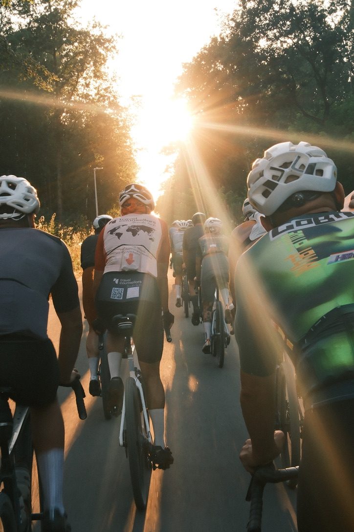 Groep gravelrijders rijdt in tegenlicht door het bos bij zonsondergang